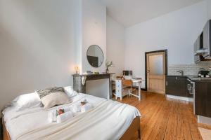 a bedroom with a large white bed and a kitchen at Huswell - Charming studio in the center of Antwerp in Antwerp