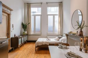 a room with a bed and a table with a mirror at Huswell - Charming studio in the center of Antwerp in Antwerp +14 photos