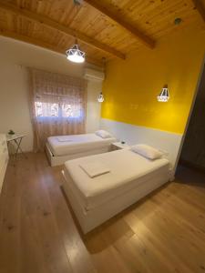 two beds in a room with a yellow wall at Villa Perikli in Delvinë