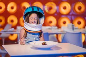 a little girl wearing a helmet with a bowl of food at Nickelodeon Hotels & Resorts Punta Cana - Gourmet All Inclusive by Karisma in Punta Cana