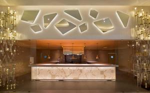 a lobby with a counter and chandeliers at Nickelodeon Hotels & Resorts Punta Cana - Gourmet All Inclusive by Karisma in Punta Cana