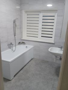 a white bathroom with a tub and a sink at FB kotedžo apartamentai 