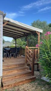 a wooden deck with awning and a table and chairs at MOBILHOME Margueritte in Lattes