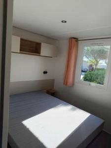 a small bedroom with a bed and a window at MOBILHOME Margueritte in Lattes