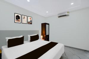 a bedroom with a large white bed with black and white pillows at Super Townhouse Oak Bachupally Medical College Formerly SV Hotels in Lingampalli +22 photos