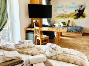 a room with a desk and a table with a television at Alpen Family Hotel Someda in Moena