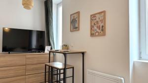 een woonkamer met een tv en een tafel met 2 krukken bij Le Confortable Centre Ville in Mâcon