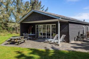 a picnic table and chairs in front of a cabin at 406-Vestervig-Bekkasinvej-6 in Vestervig