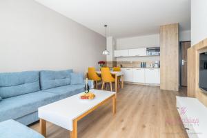 Una sala de estar con un sofá azul y una mesa. en Your Holidays Bel Mare 217D, en Międzyzdroje