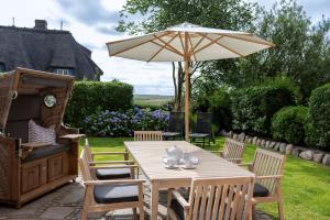 a table and chairs with an umbrella in a yard at Kairem Ingiwai 22c in Keitum