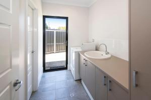 a white bathroom with a sink and a window at Tidal Wave Hideaway in Broadwater +10 photos