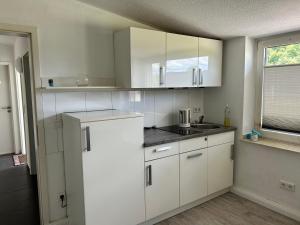 a kitchen with white cabinets and a sink and a window at Reitsportzentrum Lichtenholz in Hamminkeln