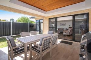 a patio with a wooden table and chairs at Tidal Wave Hideaway in Broadwater