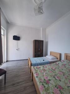 a bedroom with two beds and a tv on the wall at Mariam in Itʼkhvisi