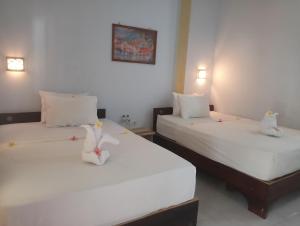 two beds in a hotel room with white sheets at BATARA Homestay in Kuta Lombok +10 photos