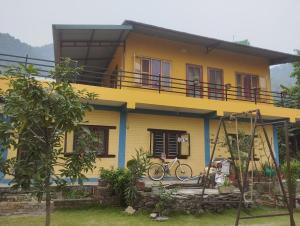 una casa gialla con una bicicletta davanti di Baloo's Family homestay a Pokhara Altre 3 foto