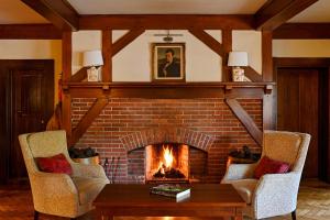 a living room with a brick fireplace with two chairs at Renvyle House Hotel & Resort in Renvyle