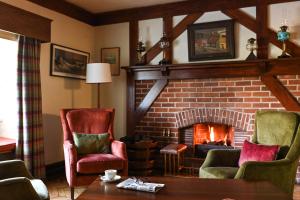 a living room with a fireplace and two chairs at Renvyle House Hotel & Resort in Renvyle