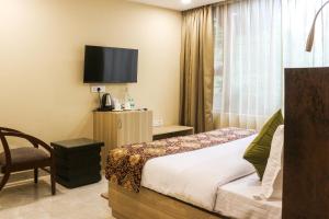 ニューデリーにあるIris Suites Kalkajiのベッドとテレビがあるホテルの部屋