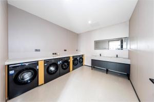 a laundry room with three washing machines and a sink at hoco好客舒旅酒店---北京站国贸店 in Beijing