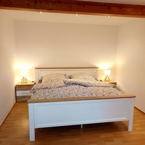 a white bed in a bedroom with two lamps at Gemütliche Ferienwohnung 