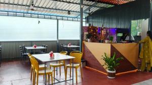 a restaurant with tables and yellow chairs and a counter at De Orchid Resort in Agonda