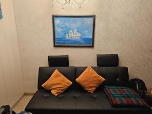 a black couch with two orange pillows on a wall at Finka Hanni in Heiligenhafen
