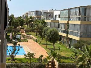 an apartment building with a swimming pool and palm trees at Appartement vue piscine - Pour Famille - Blue Beach SIDI RAHAL in Sidi Rahal
