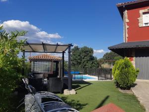 a pergola in a yard next to a pool at Casa Rural La Casita Roja in Burgohondo