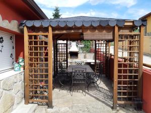 a wooden pergola with a table and chairs on a patio at Casa Rural La Casita Roja in Burgohondo