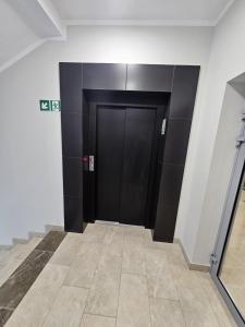 a hallway with two black doors in a building at LUXURY APARTMENTS WILCZA 15 by Marta klimatyzacja in Radom