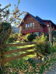 a wooden house with a fence in front of it at El Portal del Lago in Lago Puelo