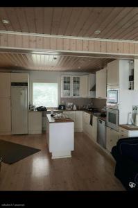 a large kitchen with white cabinets and a large window at Lake house 56 km from Helsinki in Lohja +5 photos