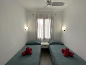 two twin beds in a room with red pillows at COSTA ARENAL 113 by SOM Menorca in Arenal d'en Castell