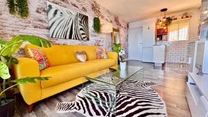 a living room with a yellow couch and a zebra painting at Ocean Soul Apartment in Santa Cruz de Tenerife