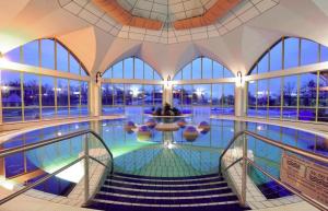 a swimming pool with stairs in a building with windows at Sárvár Fürdő Mobilházak in Sárvár +25 photos