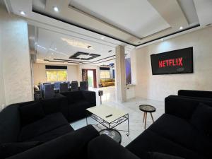 a waiting room with black couches and a tv at Rabat sidi yahya zaër in Sidi Yahia az Zaʼer