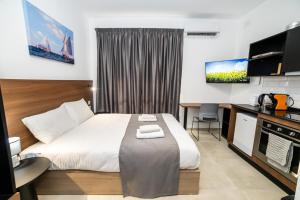 a hotel room with a large bed and a desk at Affordable Studio Apartment - by HostMT in St. Paul's Bay