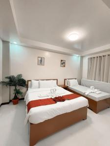 a bedroom with two beds and a couch at The Lumber Hotel and Resort in Virac