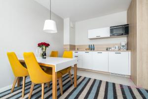 a kitchen and dining room with a white table and yellow chairs at Your Holidays Bel Mare 407D in Międzyzdroje +16 photos