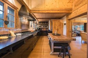 a large kitchen with wooden ceilings and a large island at Elegant Alpine Chalet with Spa in Lauenen