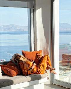 Una mujer recostada sobre una almohada frente a una ventana. en Villa Aether - Infinity Pool Villa Mykonos, en Mykonos ciudad