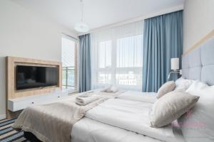 Un dormitorio blanco con una cama grande y un televisor. en Your Holidays Bel Mare 402D, en Międzyzdroje
