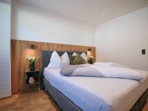a bedroom with a large bed with white sheets and pillows at BLACKSTYLE - AlpenLuxus Collection in Brixlegg