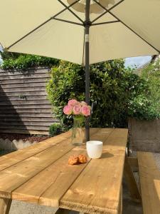 a wooden table with a vase of flowers and an umbrella at La maison de Leonie 2 chb cour wifi in Châteauroux