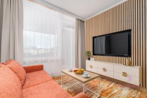 a living room with a orange couch and a flat screen tv at Your Holidays Bel Mare 109F in Międzyzdroje