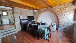 Habitación con mesa y sillas en una pared de piedra. en Agriturismo Poggiolo, en Castiglion Fiorentino