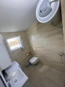 a bathroom with a toilet and a sink and a window at Garden beach house in Hamallë +9 photos