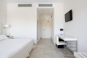 a bedroom with a bed and a desk and a television at Hotel Atlántico in Zahara de los Atunes