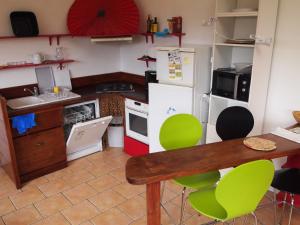 a kitchen with a table and some green chairs at Beaux retours in Dives-sur-Mer